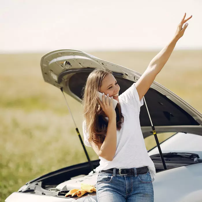 Uśmiechnięta kobieta wzywa pomoc drogową